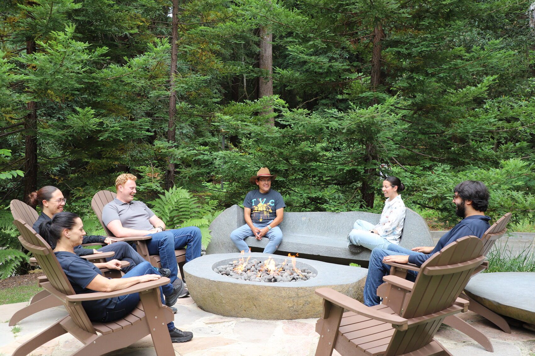 A circle of people around the fire in the redwoods at 1440 Multiversity